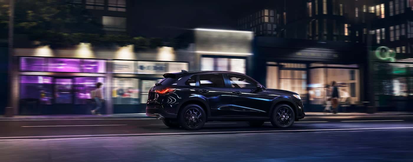 Rear of a black 2025 Honda HR-V driving down a city street.