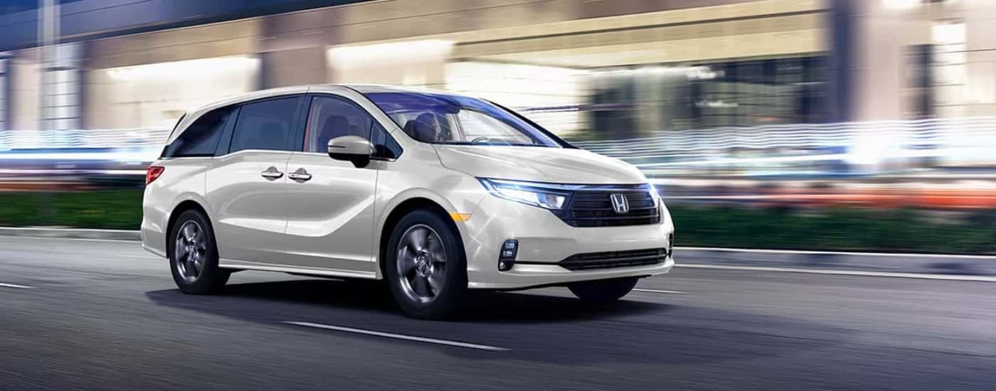 A white 2023 Honda Odussey shown driving with a blurred background.