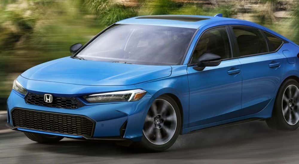 A blue 2026 Honda Civic Hatchback turning a corner on the road.
