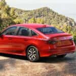 A red 2026 Honda Civic Sedan parked by a scenic view and two people.