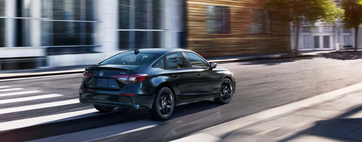 Black 2025 Honda Civic Hybrid driving through a city