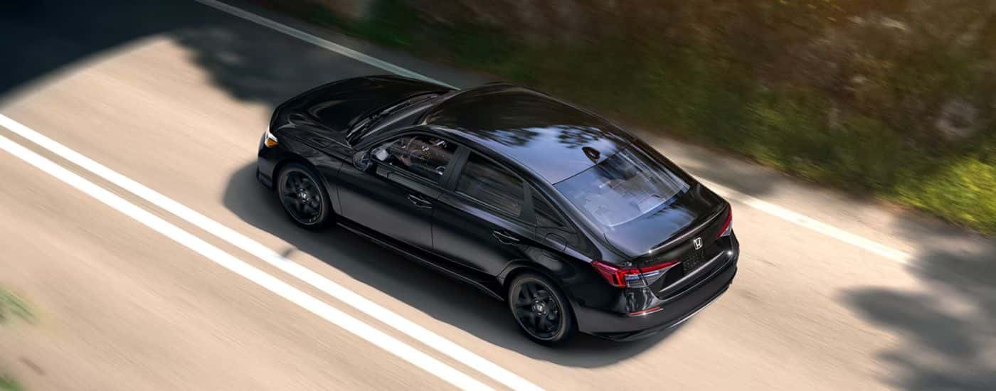 A black 2026 Honda Civic Sport driving down a road.