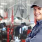 A mechanic smiling in a garage.