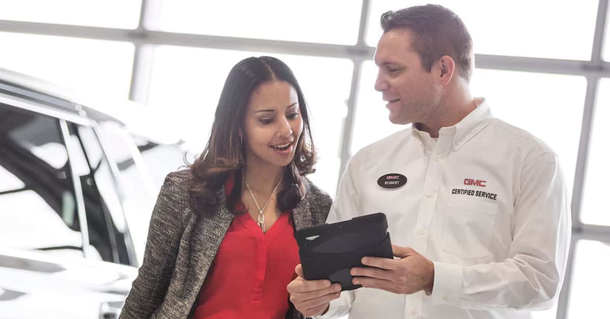 GMC service technician with customer by car