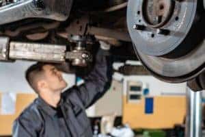 Mechanic Working On Under An Elevated Car