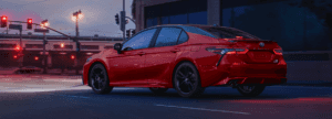 2023 Toyota Camry driving down road at dusk