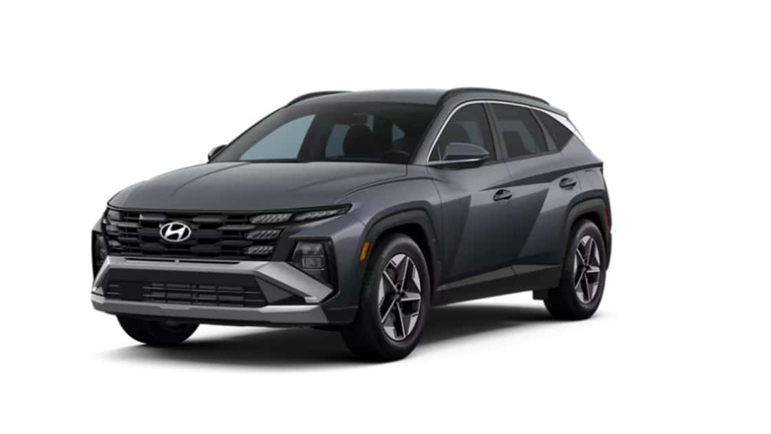 Gray Hyundai Tucson SUV shown in front three-quarter studio view with modern grille, sharp lighting, and alloy wheels.