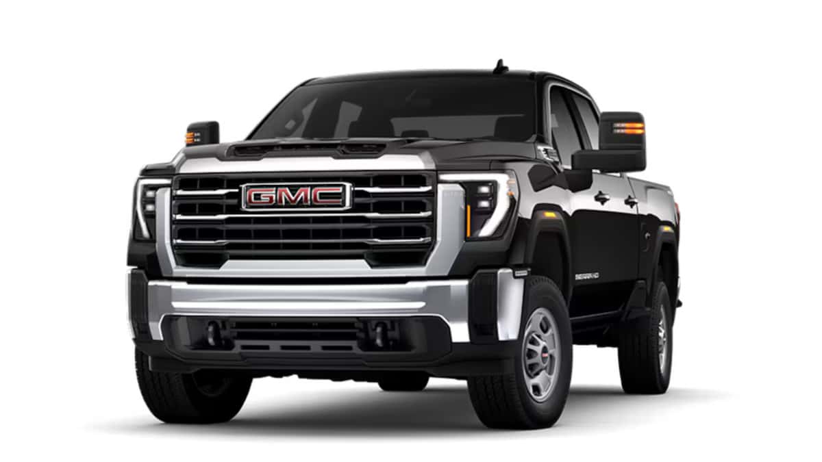 2026 GMC Sierra HD in black shown in a front three-quarter studio view with bold chrome grille and towing mirrors.