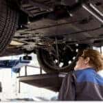 Subaru service technician draining oil from a vehicle elevated on a lift.