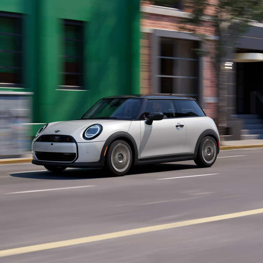 2 door hardtop MINI Cooper driving on a city street.