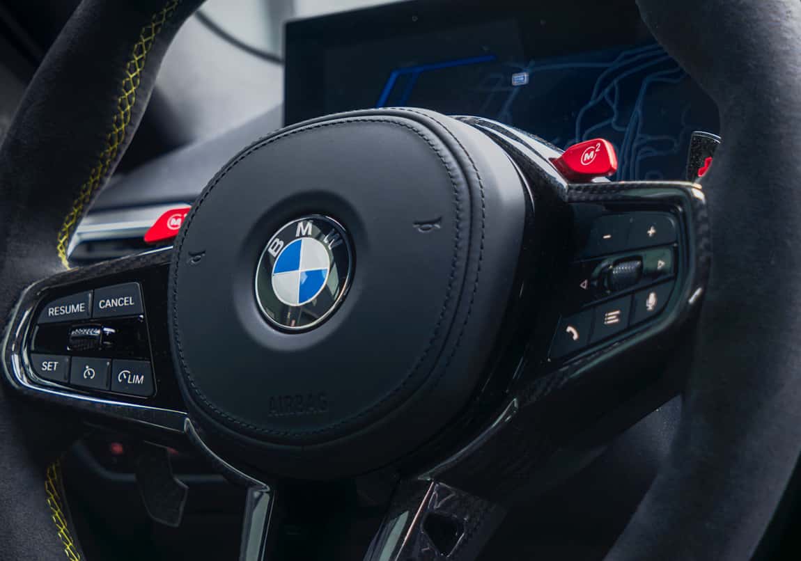 Close up of BMW steering wheel with integrated controls and digital display.