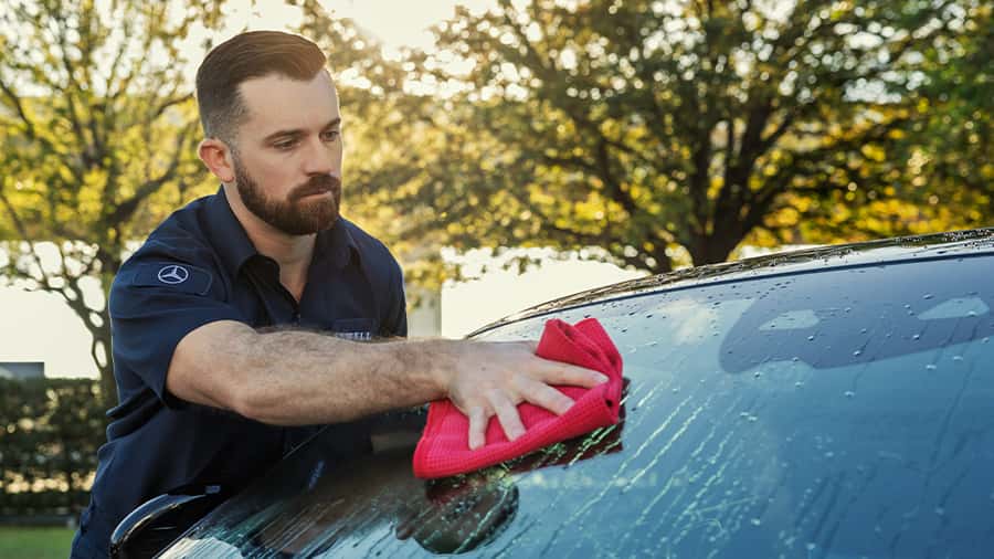 Sewell car wash associate washing a customer's vehicle's window.