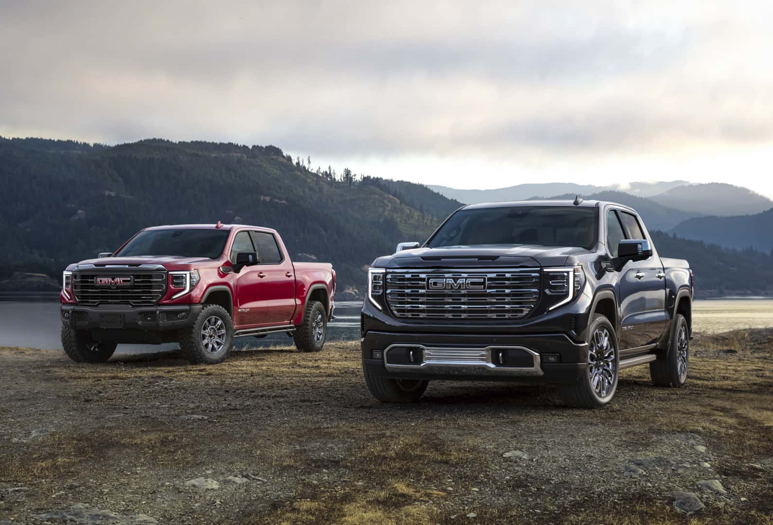 Two GMC Sierra on a dirt road.