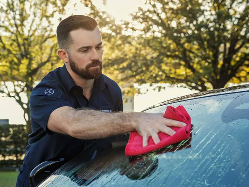 Sewell car wash associate washing a customer's vehicle's window.