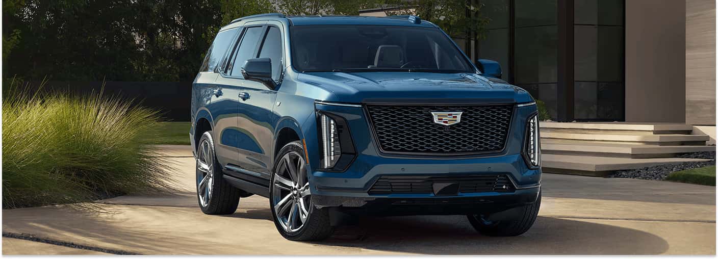 Front three-quarter view of a blue 2026 Cadillac Escalade SUV parked in a driveway.