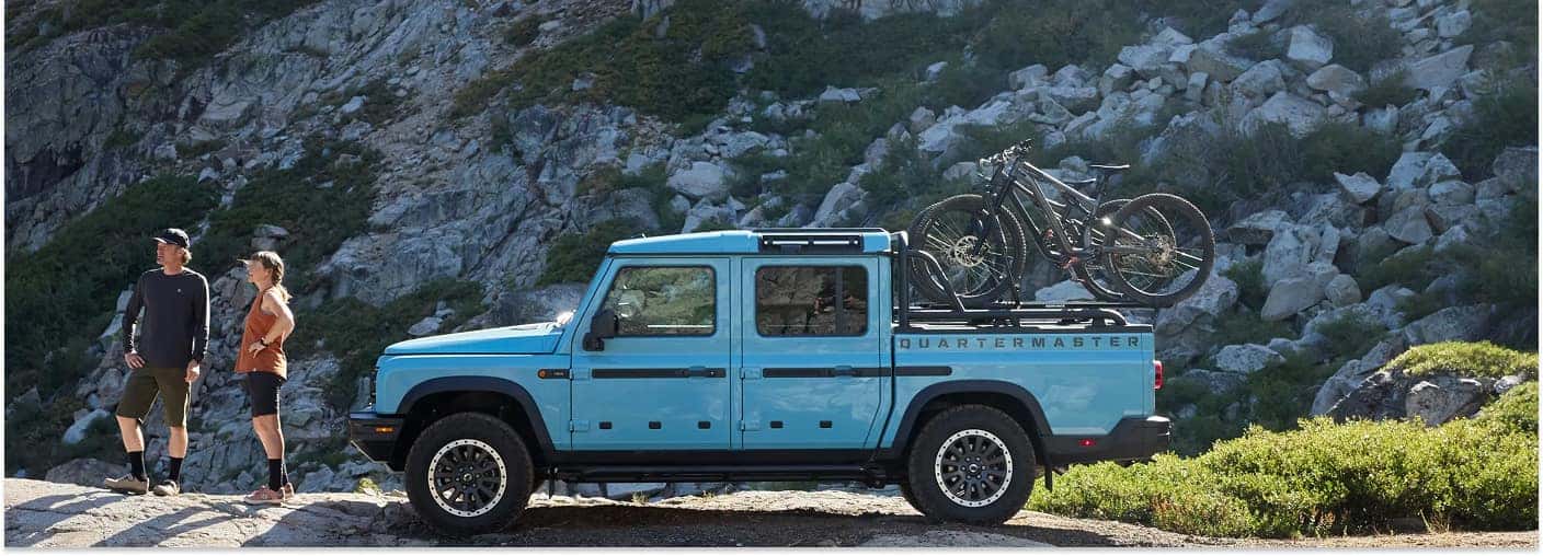 Side view of a blue 2026 INEOS Grenadier Quartermaster with mountain bikes in the bed rack.