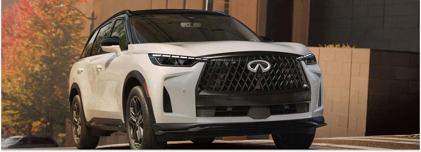 Front three-quarter view of a white 2026 INFINITI QX60 with a black roof parked on a street.