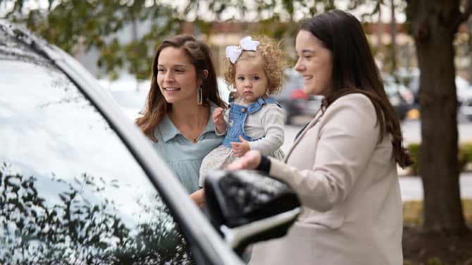 Sewell Lexus of Dallas associate helping a customer holding their child