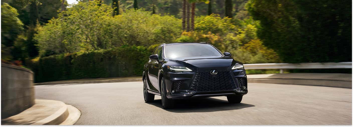 Front three-quarter view of a black 2026 Lexus RX driving on a curved road.