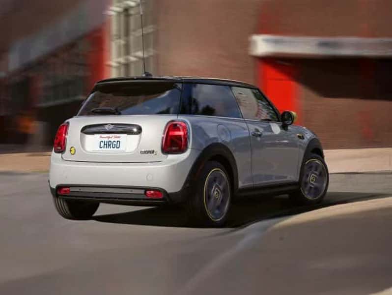 MINI Countryman SE ALL4 Electric driving in city setting showing rear design and compact SUV styling.
