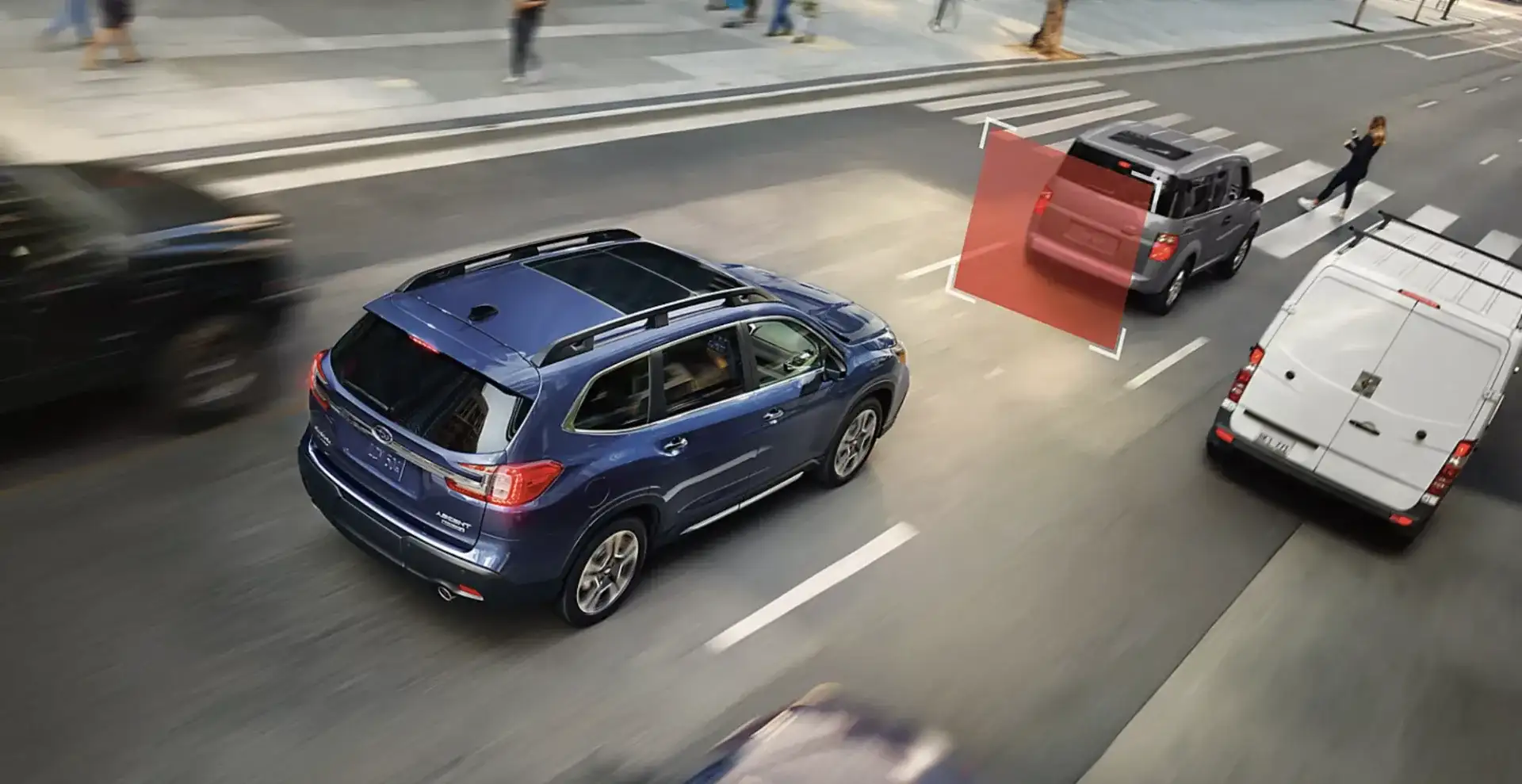 The Subaru Ascent using Subaru Eyesight to detect a vehicle ahead near a crosswalk, demonstrating automatic pre-collision braking in city traffic