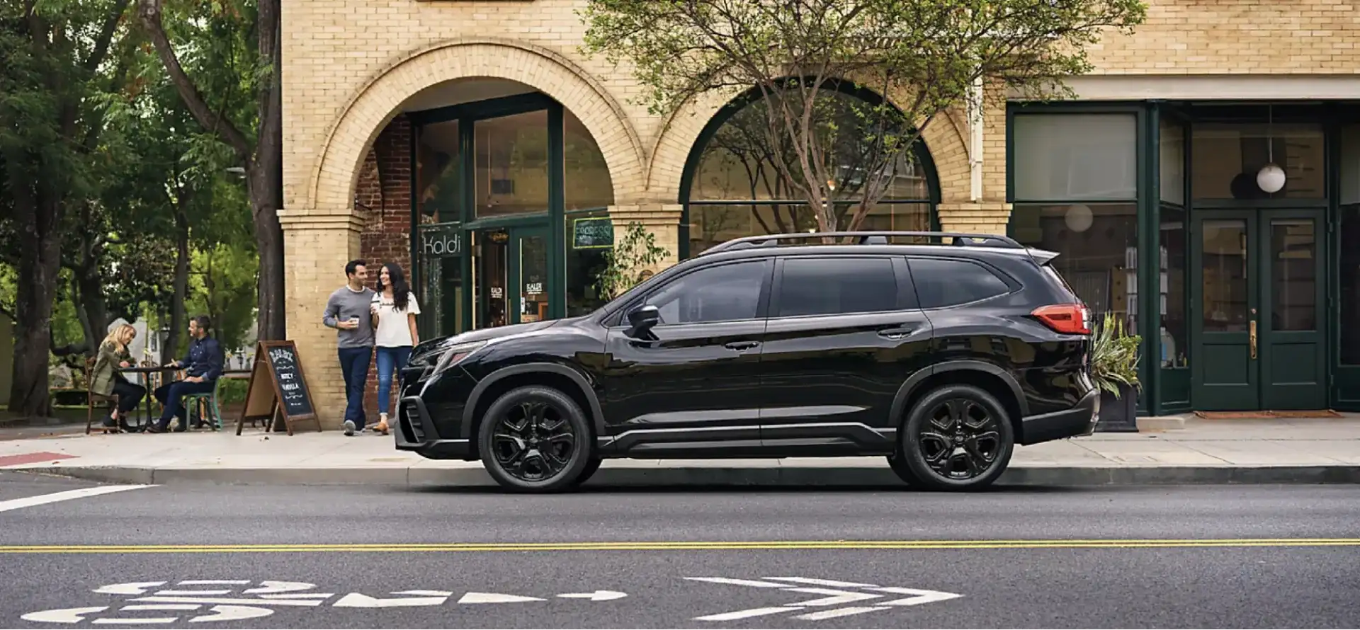The 2026 Subaru Ascent parked on a downtown street outside a brick coffee shop