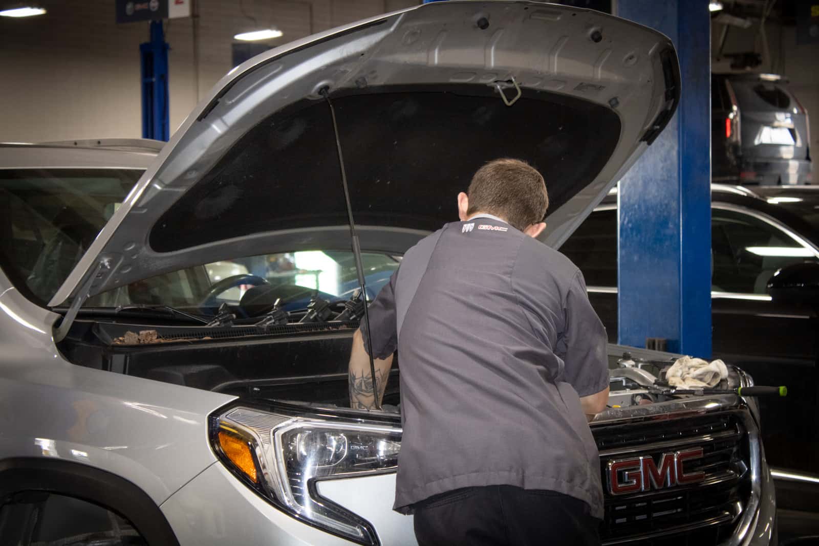 Sims Auto Park service technician working under the hood of a GMC