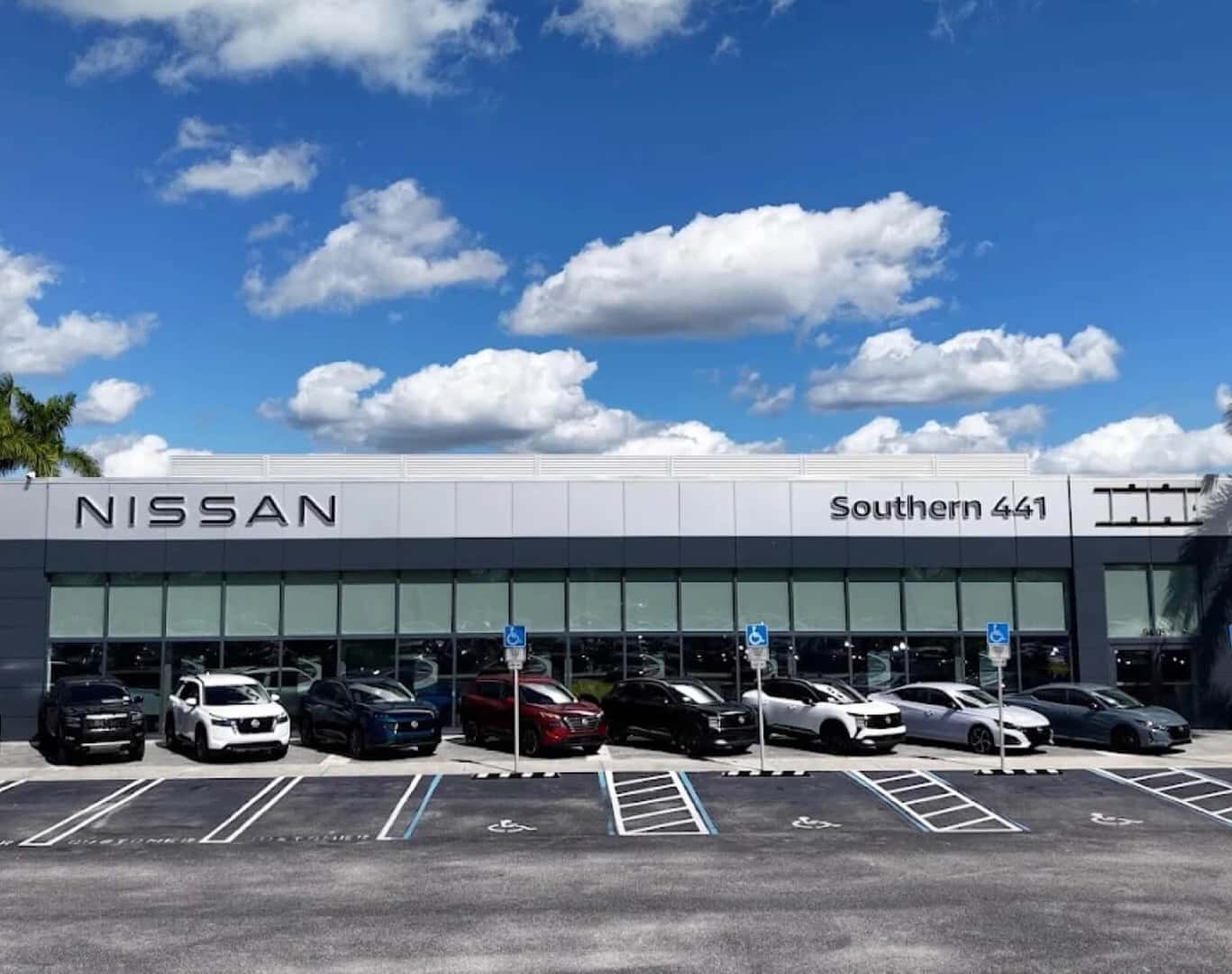 Exterior wide view of the Southern 441 Nissan dealership building with vehicles parked out front under a blue sky.
