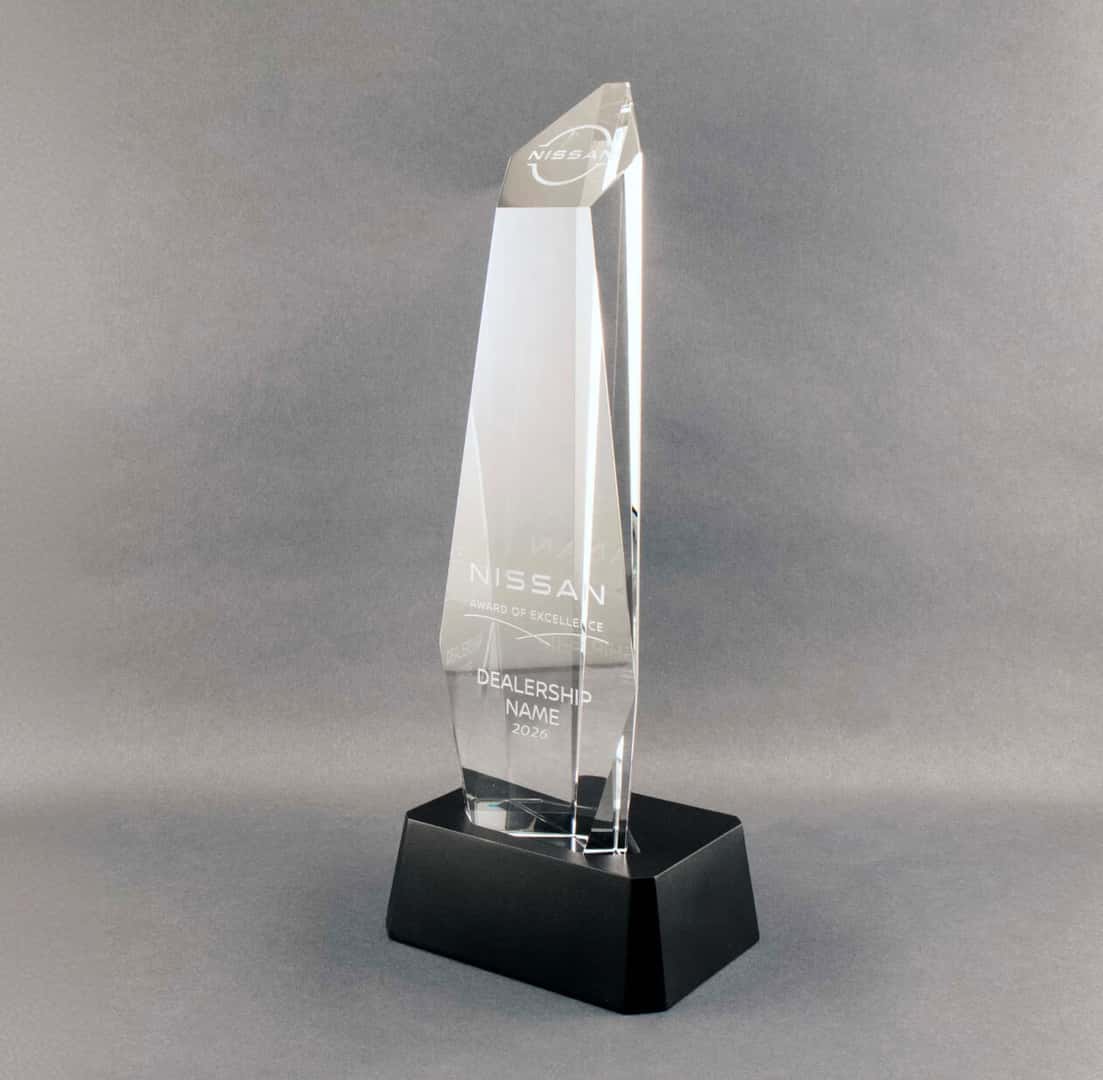 Nissan Award of Excellence crystal trophy on a black base, displayed against a gray studio background.