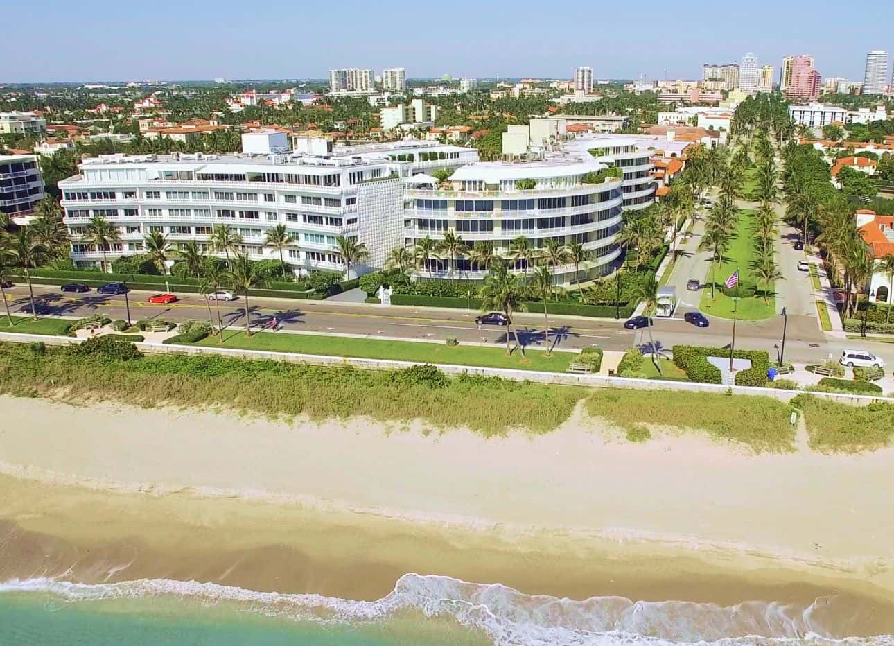 Aerial view of a beachfront area with palm-lined streets, buildings, and ocean shoreline.