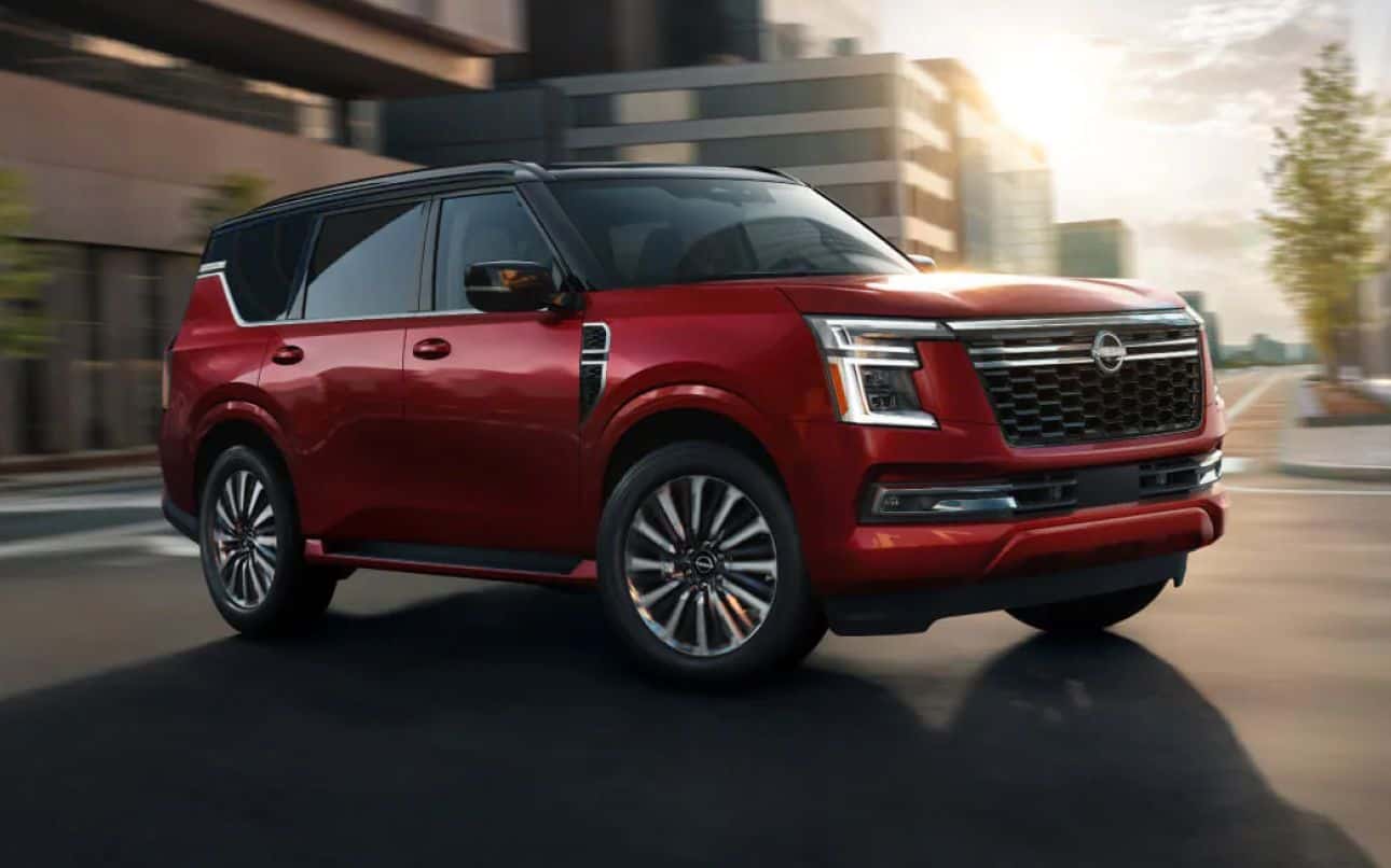 Red Nissan SUV driving through an urban area.