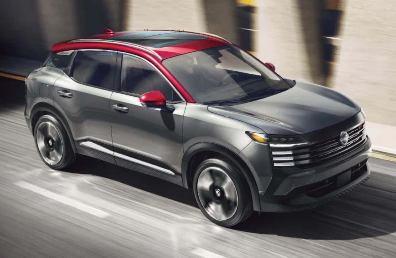 Gray Nissan SUV with a contrasting red roof driving on a city street.