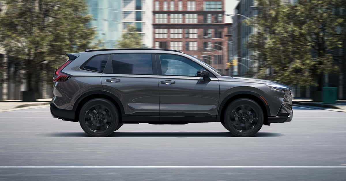 A charcoal gray Honda CR-V Hybrid on the road in a city.