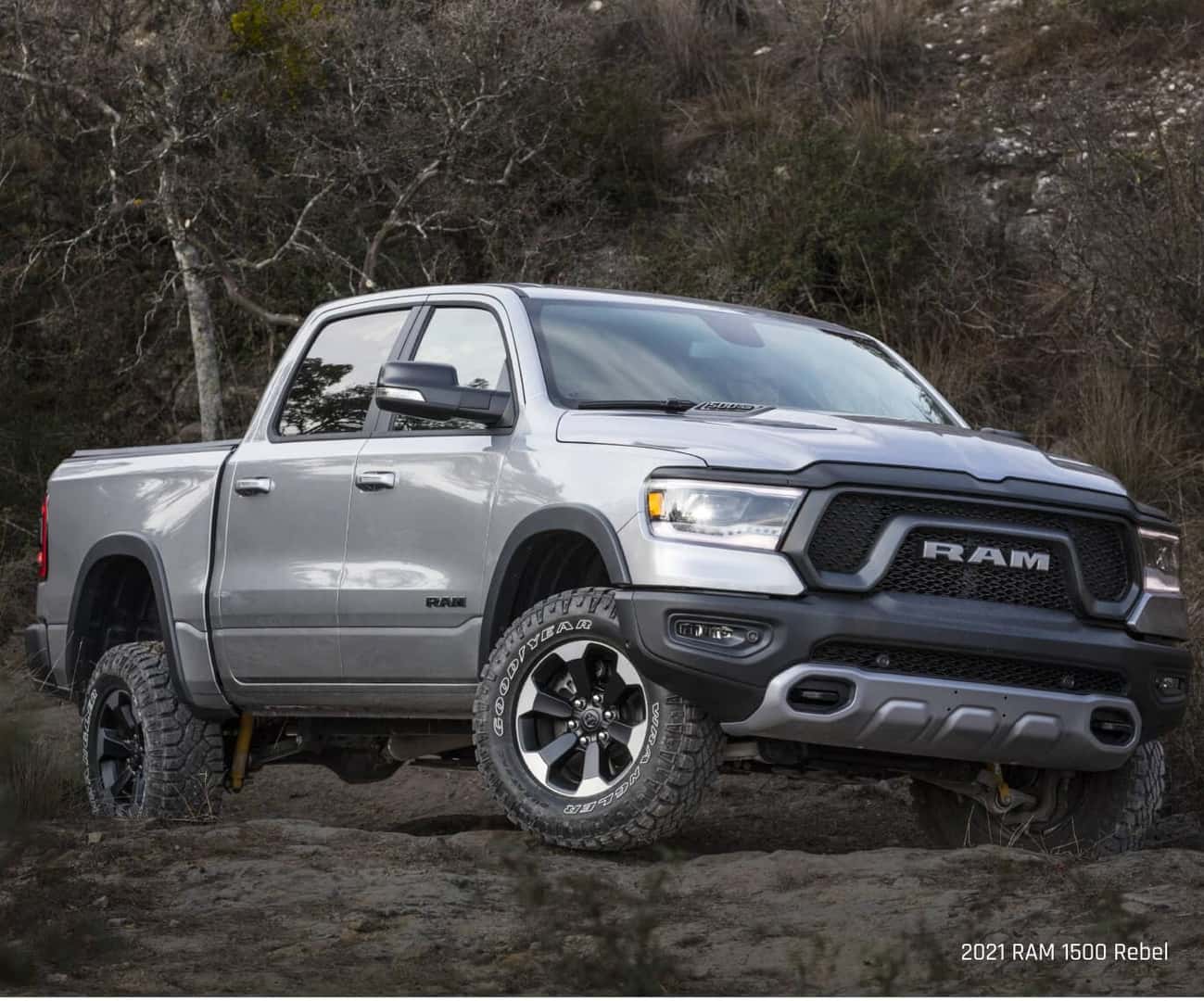 Three-quarter view of a Ram 1500 Rebel in Silver climbing an uneven, rocky trail.