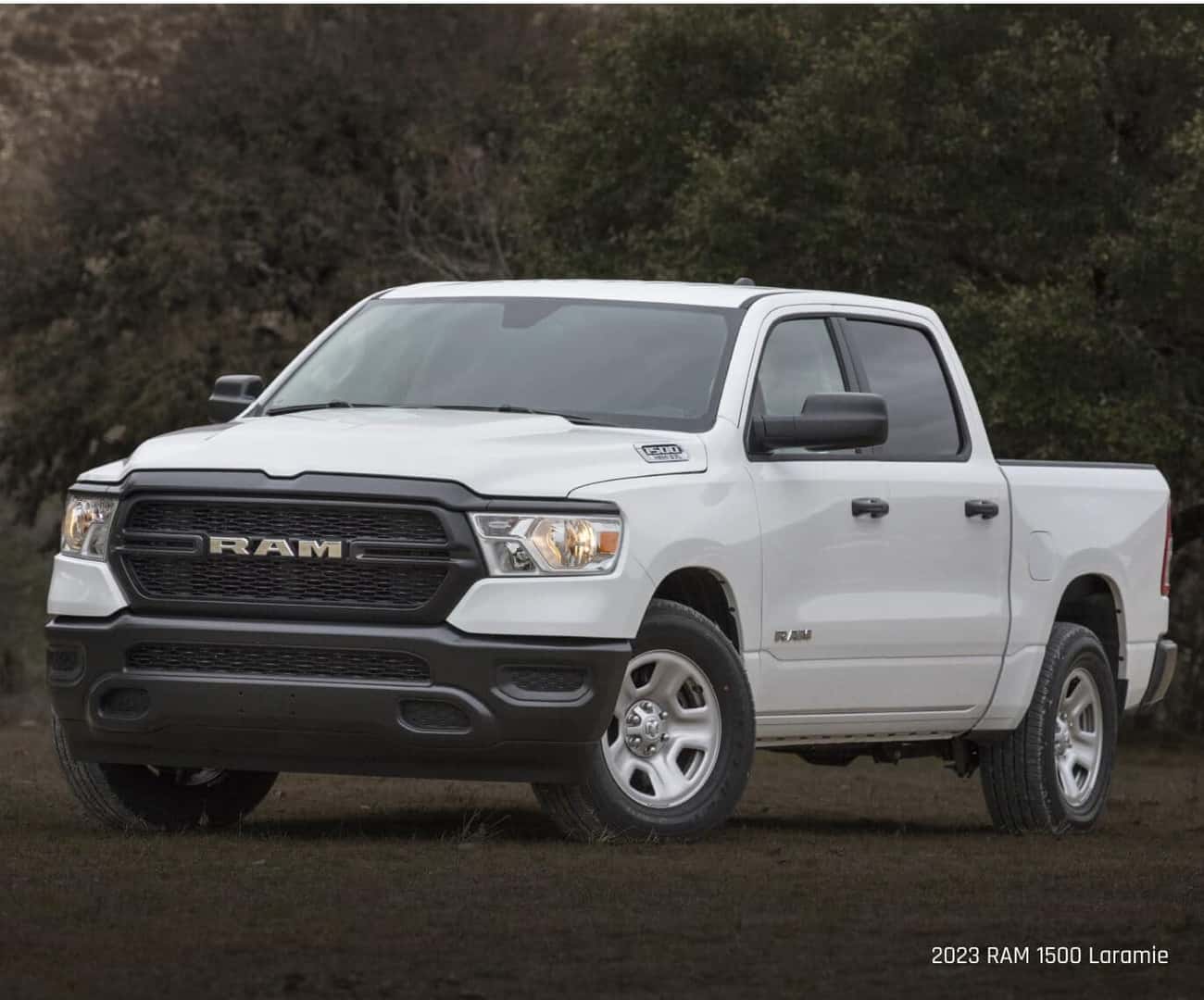 Three-quarter view of a Ram 1500 Tradesman in White parked on a dirt patch.