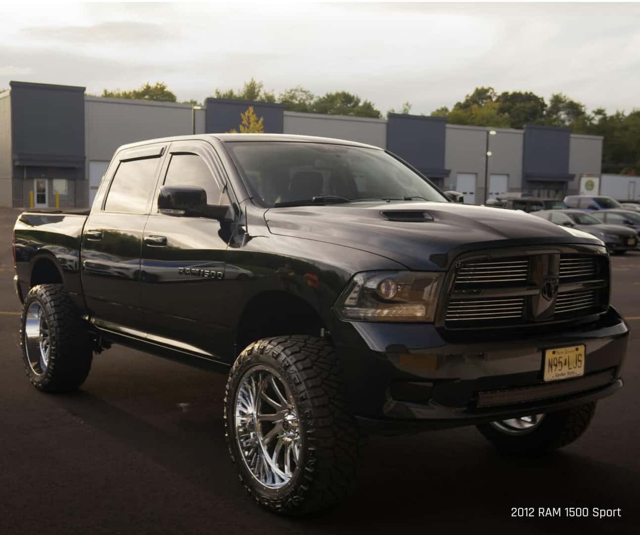 Low three-quarter view of a Ram 1500 Sport in Black parked on an asphalt lot.