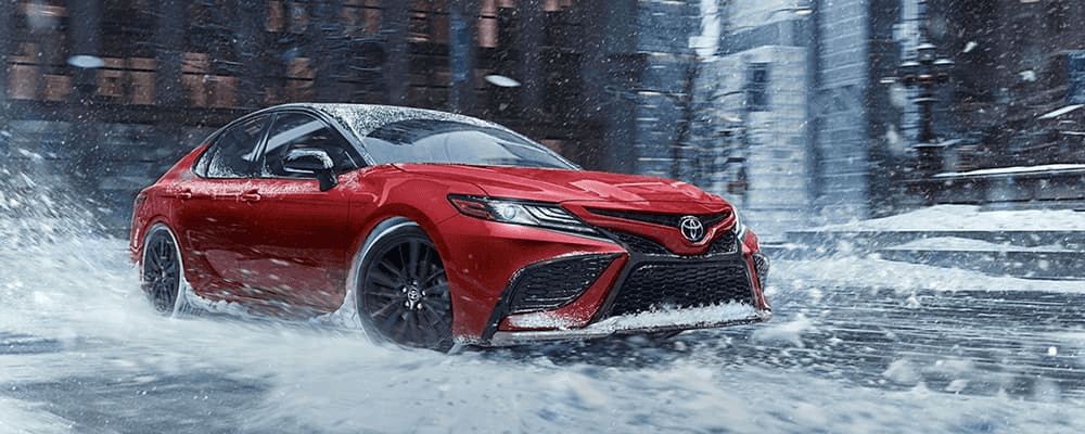 A red toyota camry drives in snow