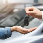 A car salesperson handing over keys to a vehicle.