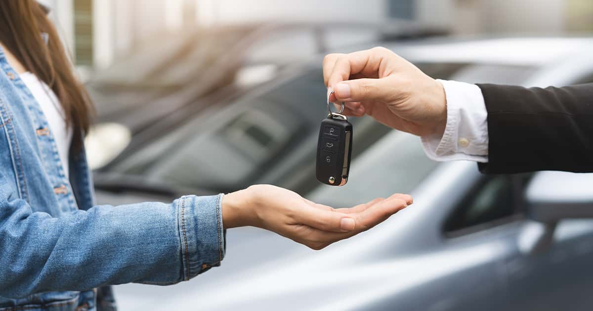 A car salesperson handing over keys to a vehicle.