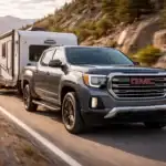 GMC Canyon towing a travel trailer on a scenic highway at sunset