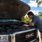 Man working on truck in sunny driveway