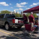 2026 Ford F-150 SuperCrew tailgate down at a Montgomery Alabama football game-day parking lot, fans tailgating in September heat