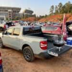 2026 Ford Maverick tailgate setup in a stadium parking lot with grill and cooler, game-day afternoon light