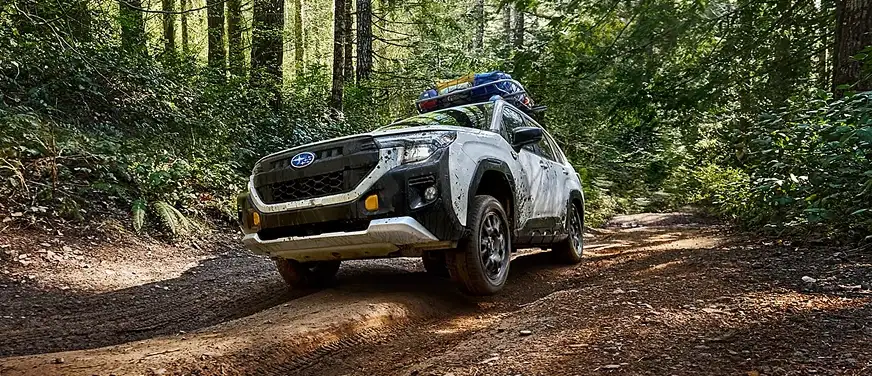 White 2026 Subaru Forester Wilderness driving over a rutted forest trail