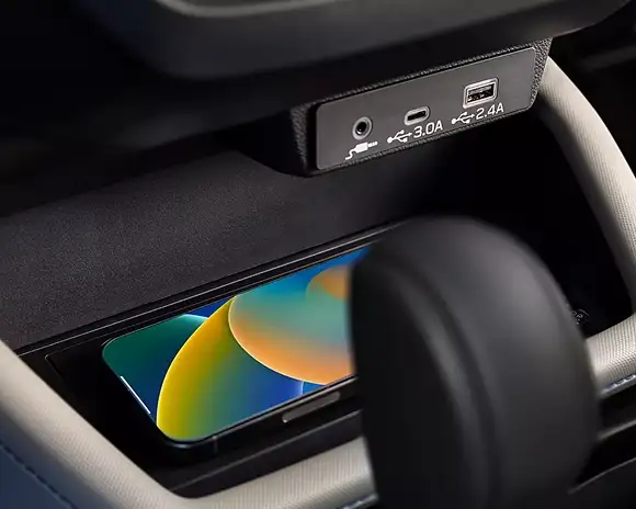 Wireless charging pad holding a smartphone beside USB-A and USB-C ports in the 2026 Subaru Forester
