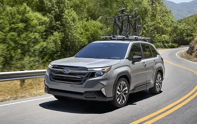 Silver 2026 Subaru Forester carrying bikes on a roof rack along a mountain road