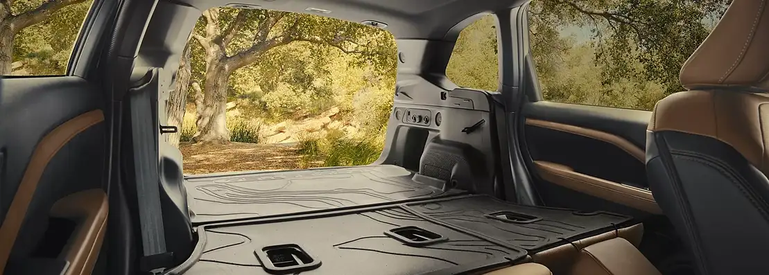Rear seats folded flat in the 2026 Subaru Forester, tailgate open to a forest