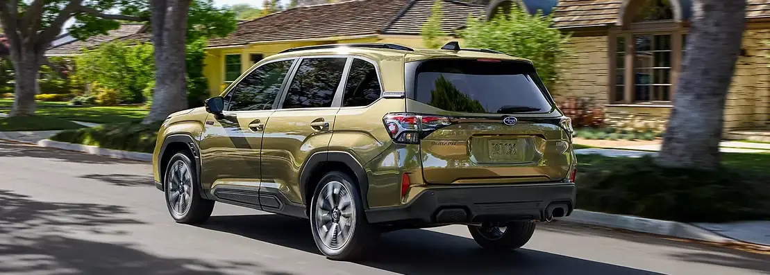 Green 2026 Subaru Forester driving through a tree-lined neighborhood