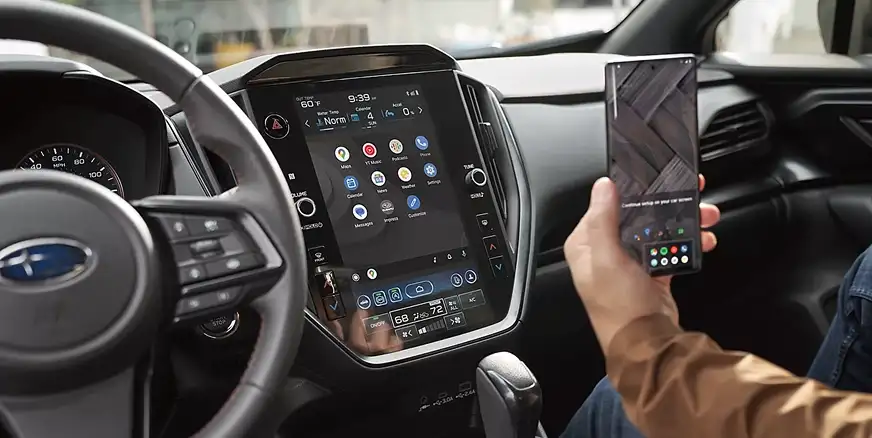 2026 Subaru Impreza dashboard touchscreen with a driver holding a smartphone