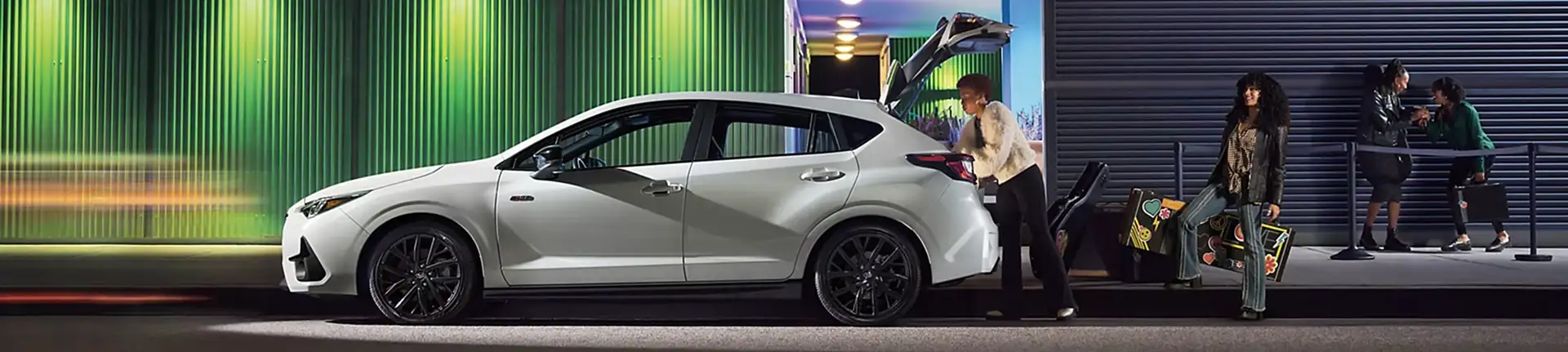 White 2026 Subaru Impreza parked at night outside a lit building